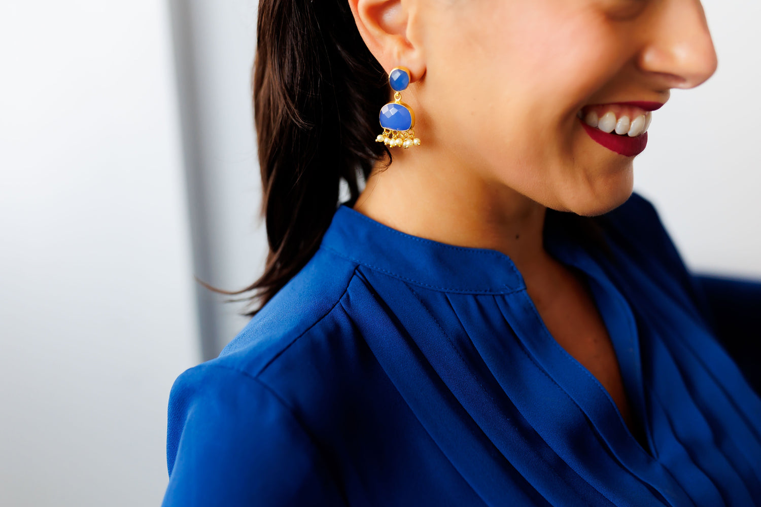 Blue gemstone drop earrings with gold fringe, worn on model
