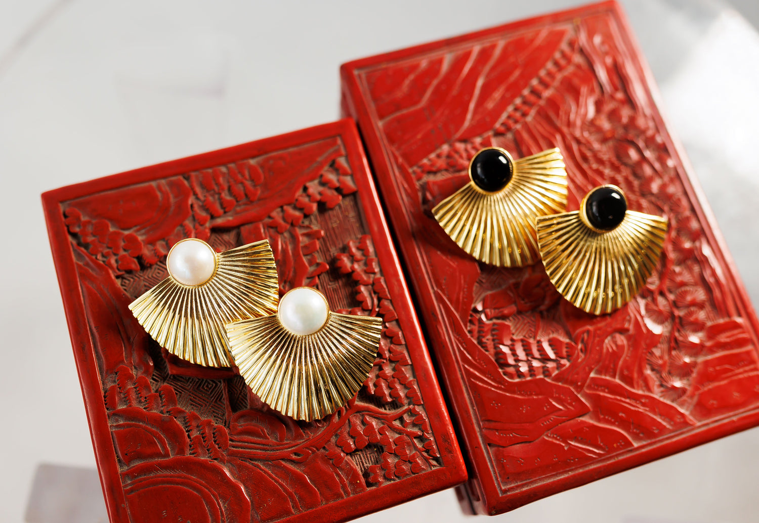 Pair of gold fan earrings with black stones in red decorative boxes
