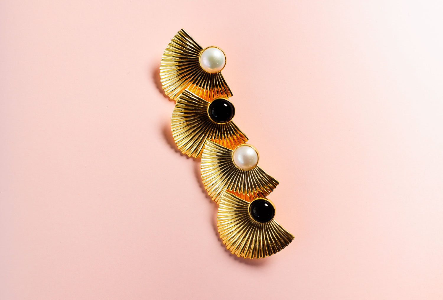 Gold-tone fan earring with pearl center and black stones, close-up