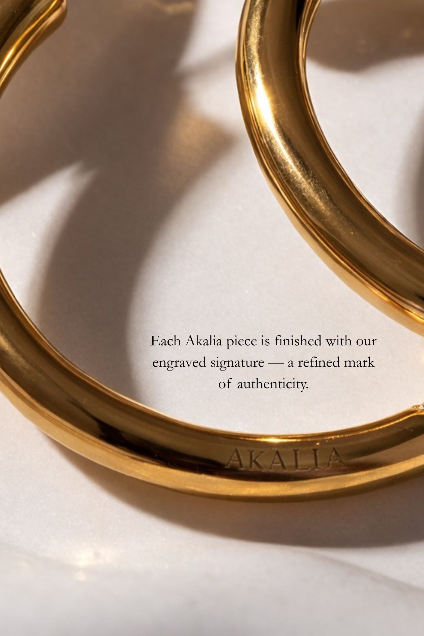 Gold bracelet close-up with engraved signature detail and brand lettering