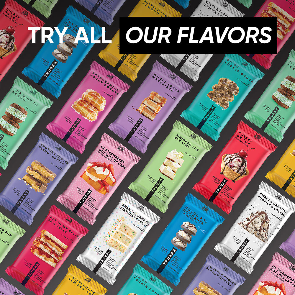 Assorted TRUBAR protein bar boxes and pouches on a colorful display