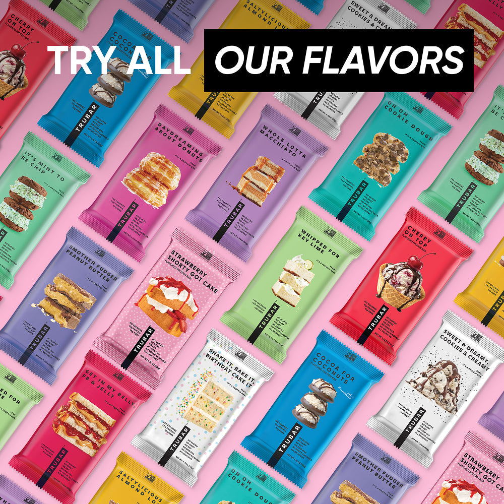 Assorted TRUBAR protein bar lineup on colorful background, Strawberry Shorty Got Cake visible