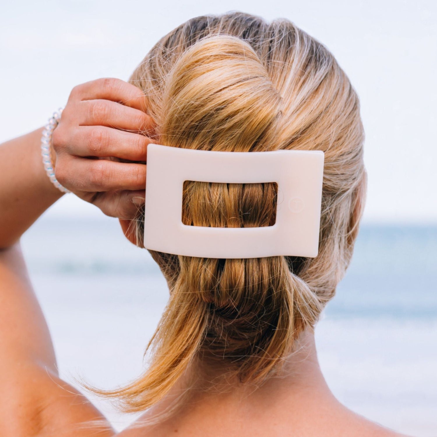 Large almond beige flat hair clip holding blonde hair in a low bun