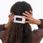 Beige medium flat rectangle hair clip held near hair with rectangular opening