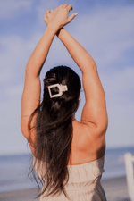 Beige flat square hair clip holding long dark hair in place