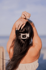 Beige flat square hair clip securing long dark hair