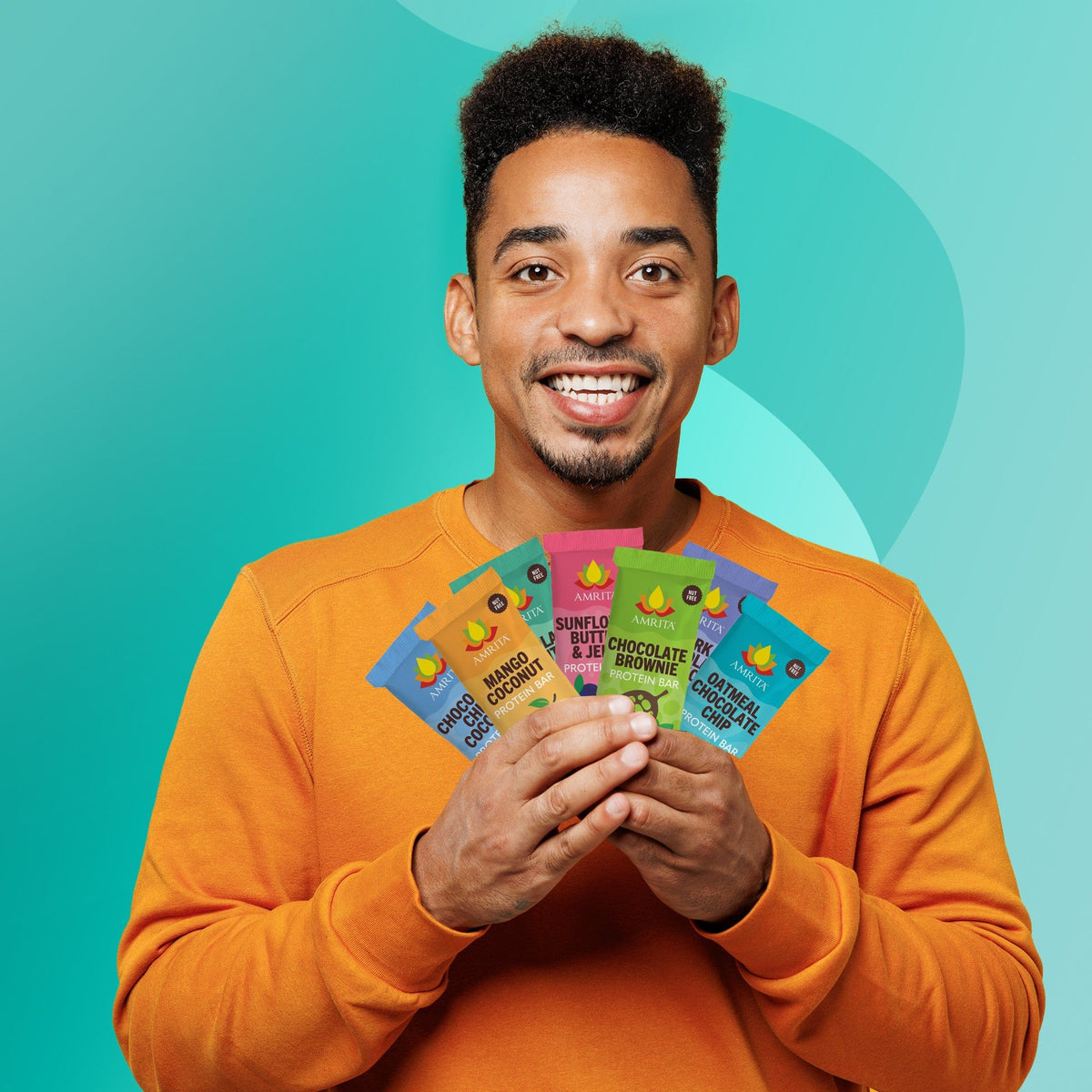 Assorted Amrita protein bars starter pack held by a smiling man, multiple wrappers