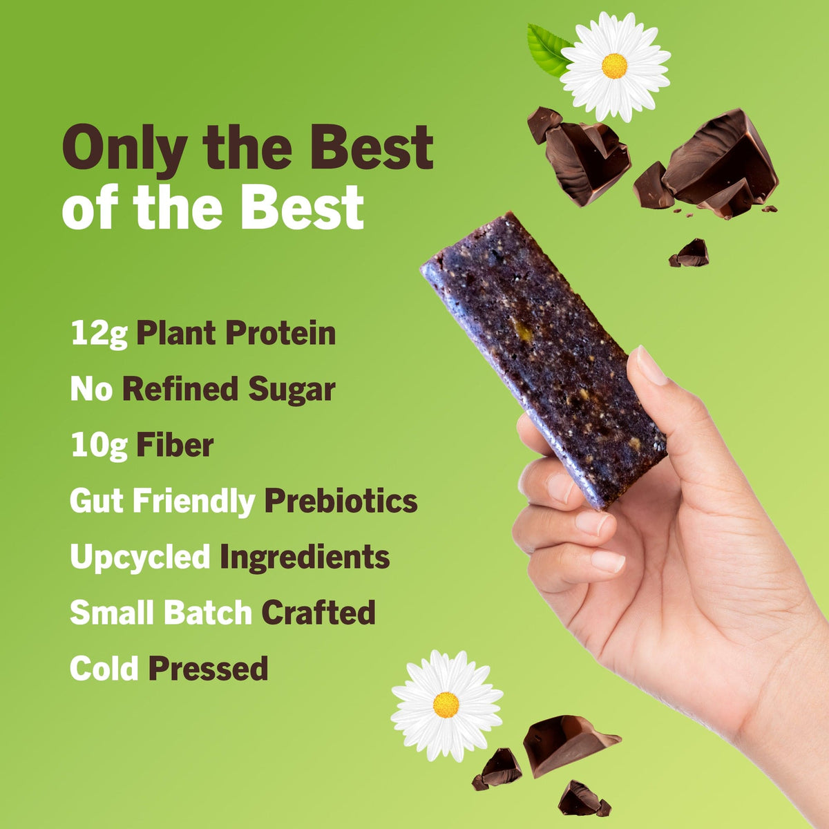 Chocolate brownie protein bar piece held in hand, dark bar with green wrapper nearby.