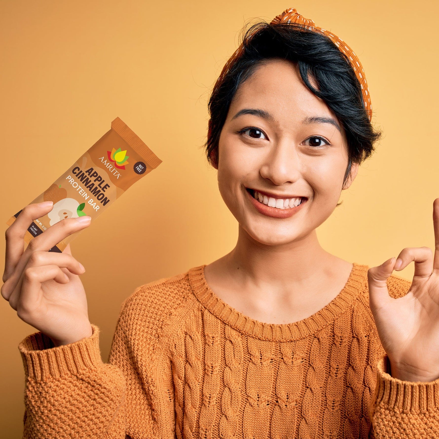 Apple cinnamon protein bar wrapper held in hand, brown AMRITA logo