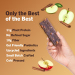 Apple cinnamon protein bar held in hand, dark purple bar piece with fruit toppings