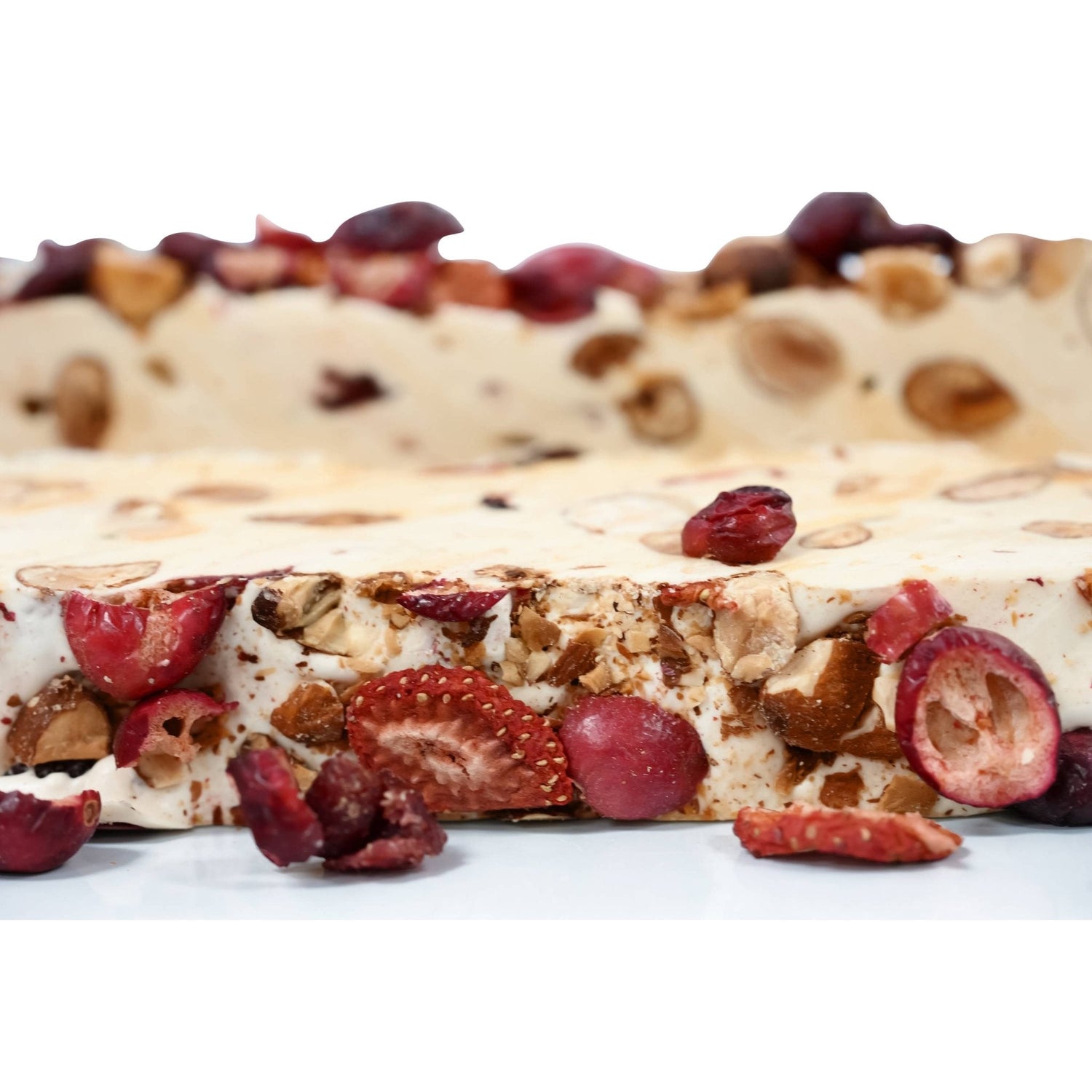 Nougat bar close-up with red fruit chunks, sliced almonds, and creamy white base