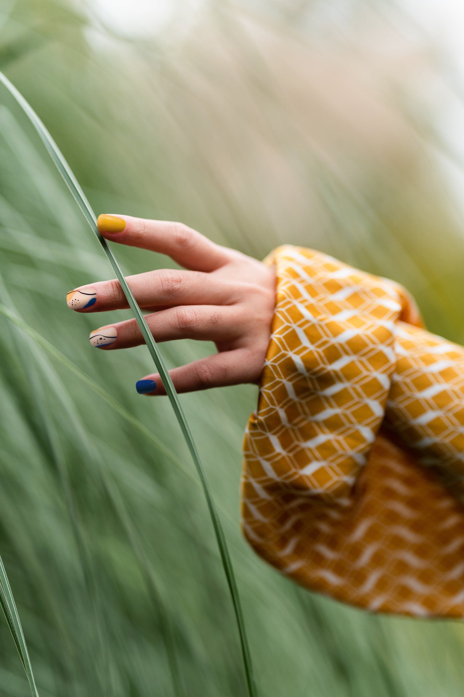 Hand wearing orange and blue press-on nails