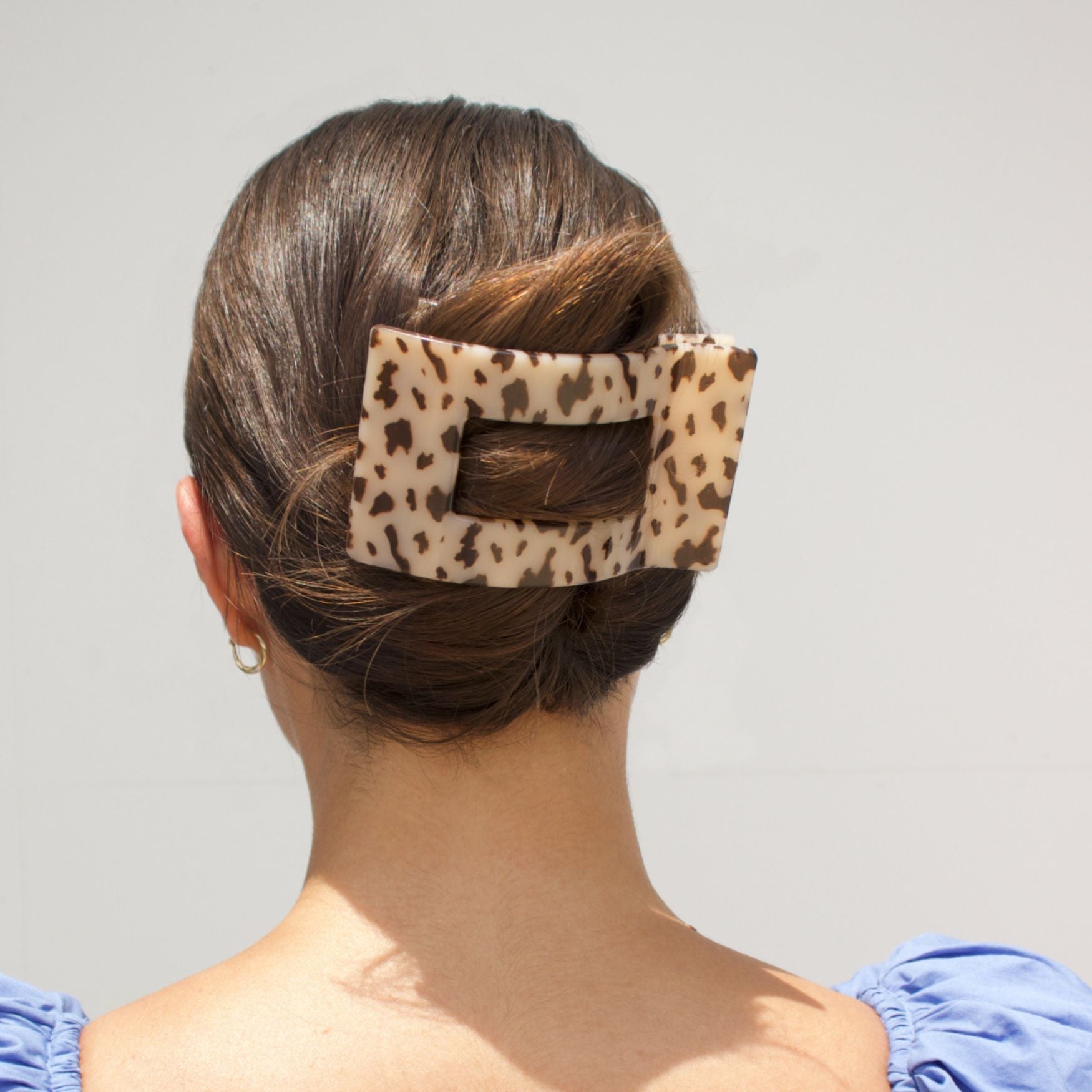 Leopard-pattern flat hair clip holding hair at the back.