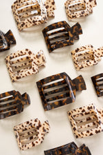 Set of flat square tortoise hair clips in beige leopard and dark brown patterns.