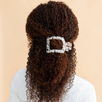 Flat square tortoise hair clip with beige leopard finish clipped in curly hair.