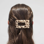 Rectangle hair clip with blonde tortoise pattern, clipped on dark hair