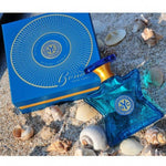 Eau de parfum bottle beside blue box, teal glass with NYC emblem