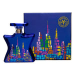 Blue perfume bottle and matching box with colorful skyline graphic and gold accents