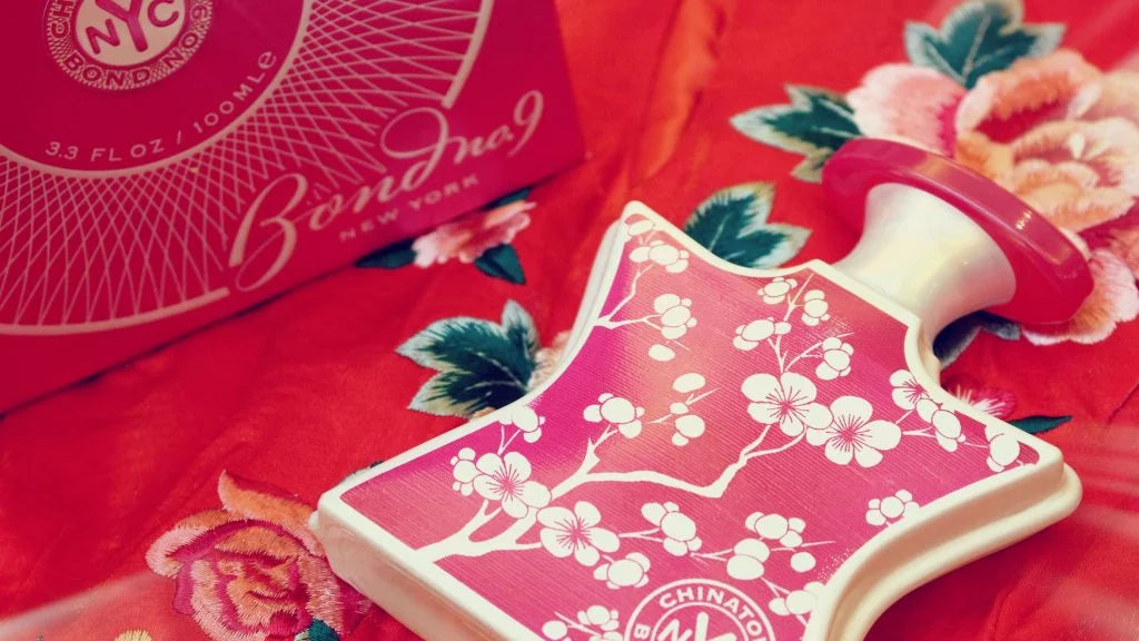 Close-up of pink eau de parfum bottle with white floral label and red sprayer cap