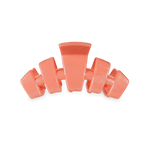 Small coral-orange claw clip with four curved teeth for holding hair.