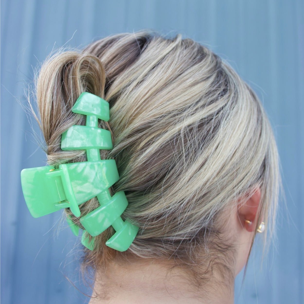 Large mint green claw clip holding up long hair in a side bun
