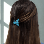 Sky-blue tiny claw hair clip clipped on dark brown hair