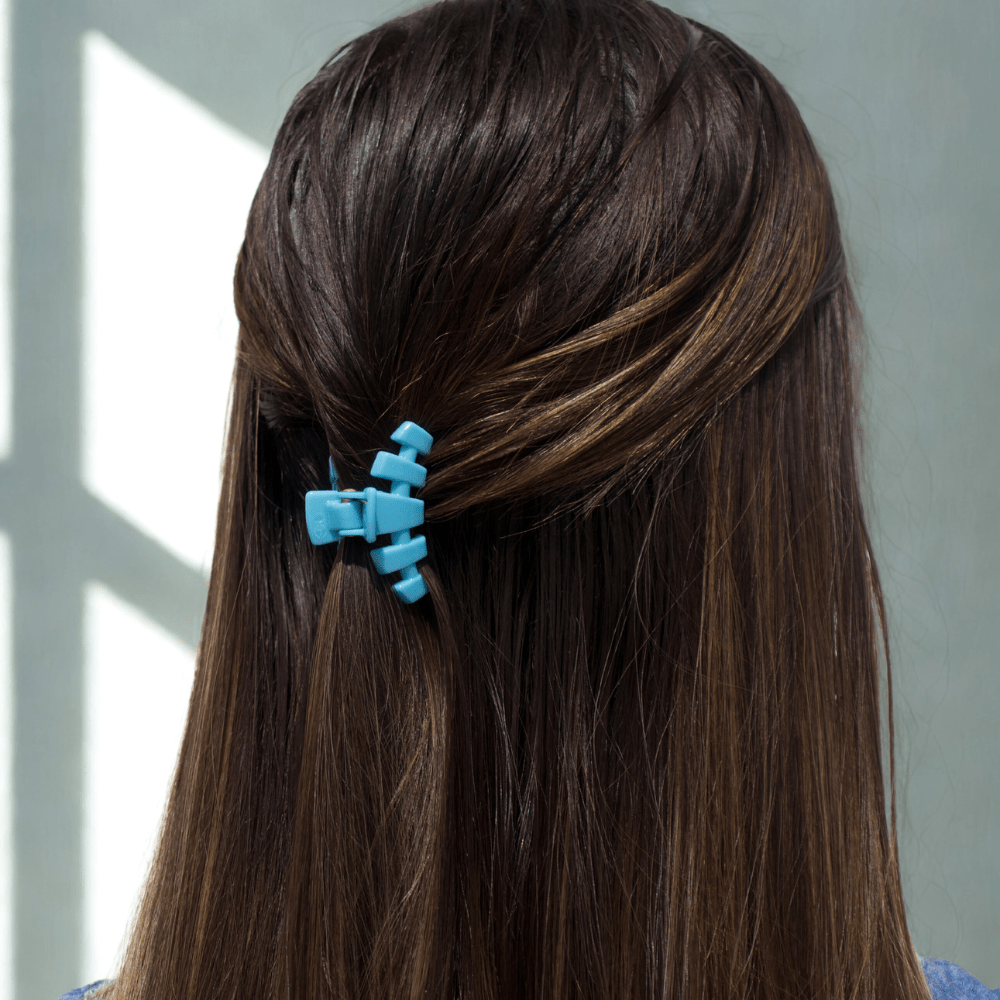 Sky-blue tiny claw hair clip clipped on dark brown hair