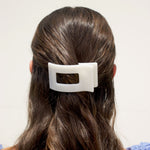 White rectangular hair clip clipped onto dark brown hair