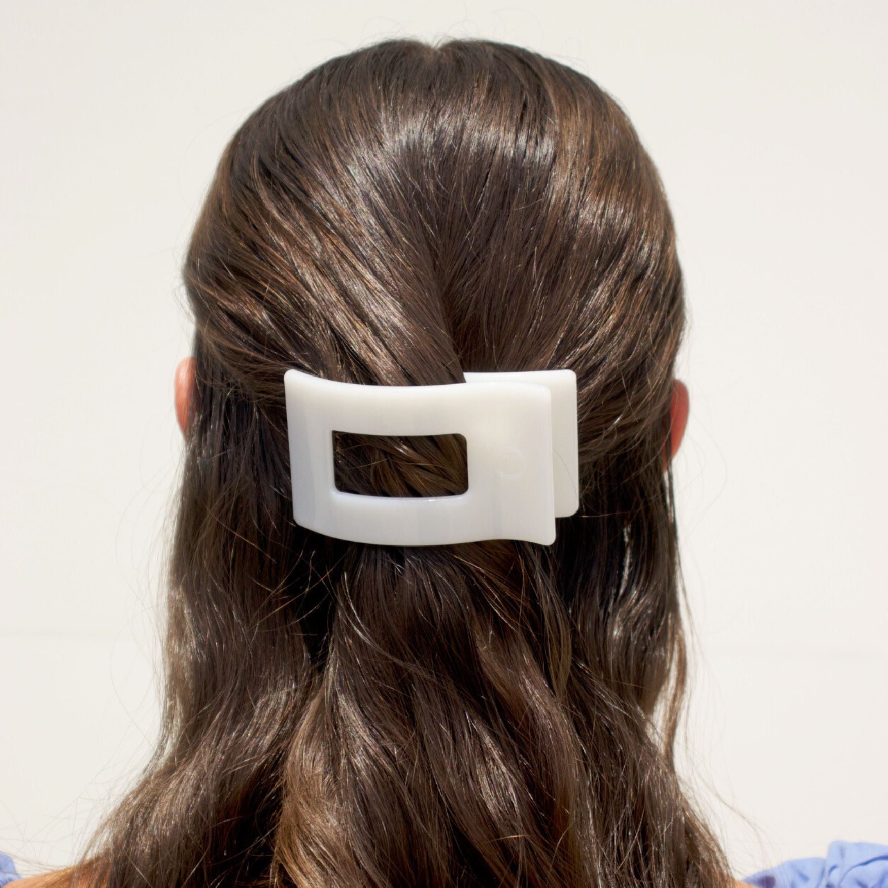 White rectangular hair clip clipped onto dark brown hair