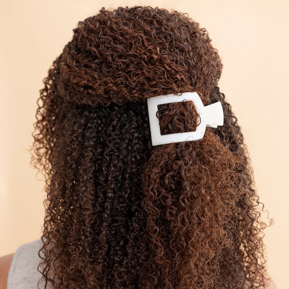 White flat square hair clip fastening curly brown hair