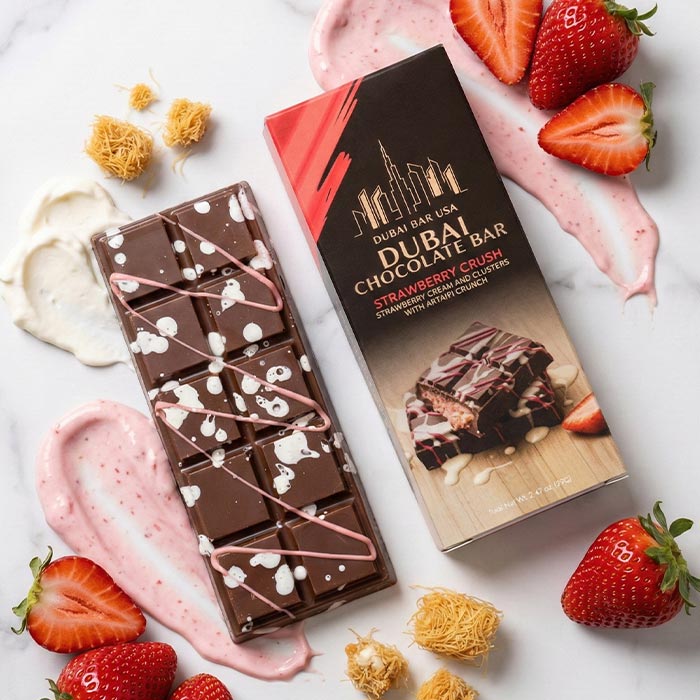 Dubai chocolate bar with white drizzle on dark chocolate beside strawberry crush box