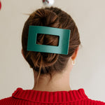 Teal green rectangular hair clip holding a bun on dark hair