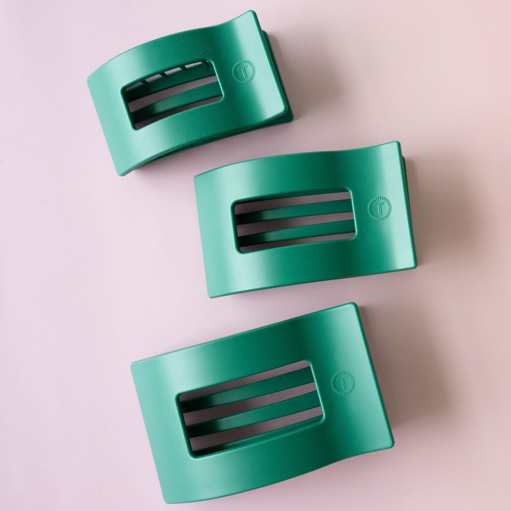 Three teal green rectangular hair clips with black teeth, set