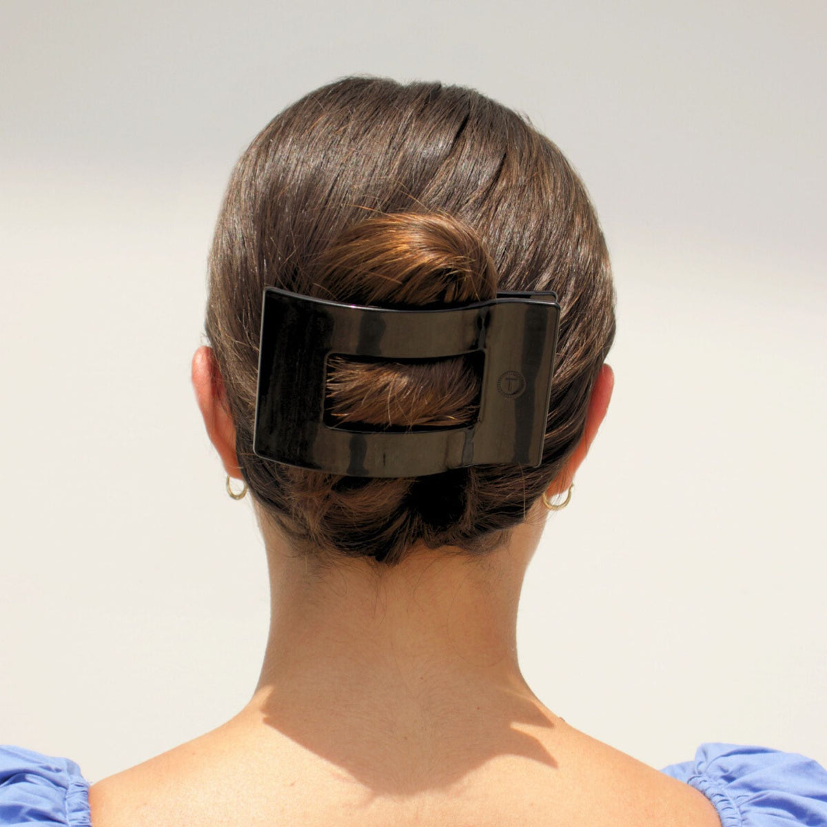 Black flat rectangular hair clip holding hair at the back of the head