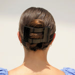 Black flat rectangular hair clip holding hair at the back of the head