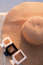 Black square hair clip with white accents attached to a straw hat
