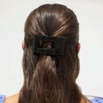 Small black flat rectangle hair clip holding hair at the back
