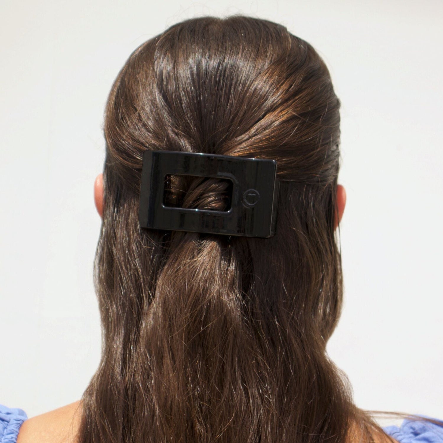 Small black flat rectangle hair clip holding hair at the back