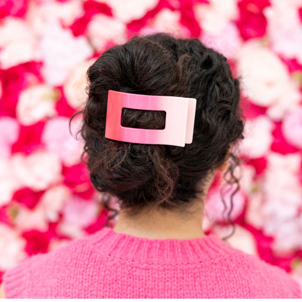 Pink rectangle hair clip clipped to curly dark hair