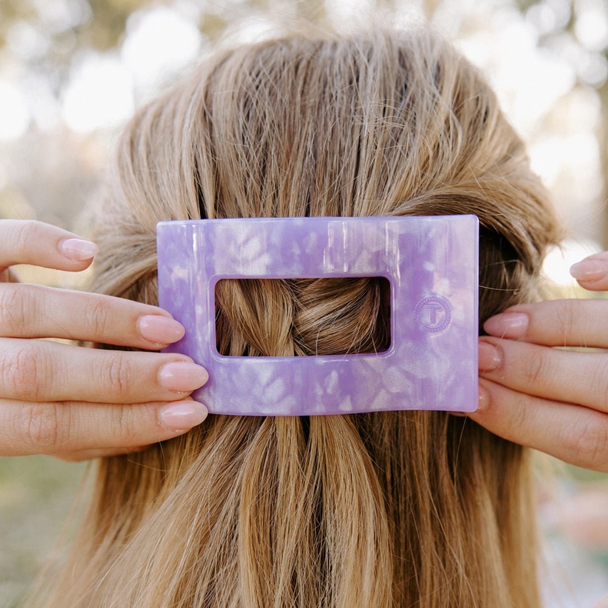 Lavender rectangular flat hair clip with marbled pattern held in blonde hair