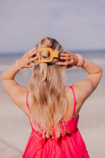 Orange square flat hair clip worn in long blonde hair, prongs visible