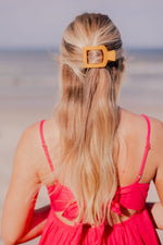 Small flat square hair clip worn in long blonde hair, orange square frame