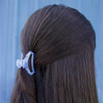 Light blue tiny hair clip holding dark hair in a side section