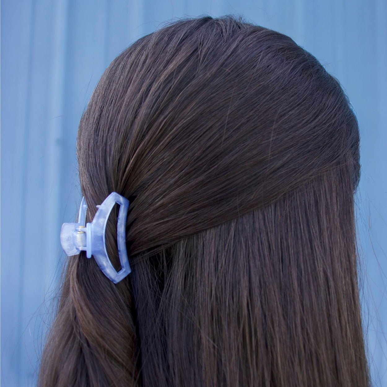 Light blue tiny hair clip holding dark hair in a side section