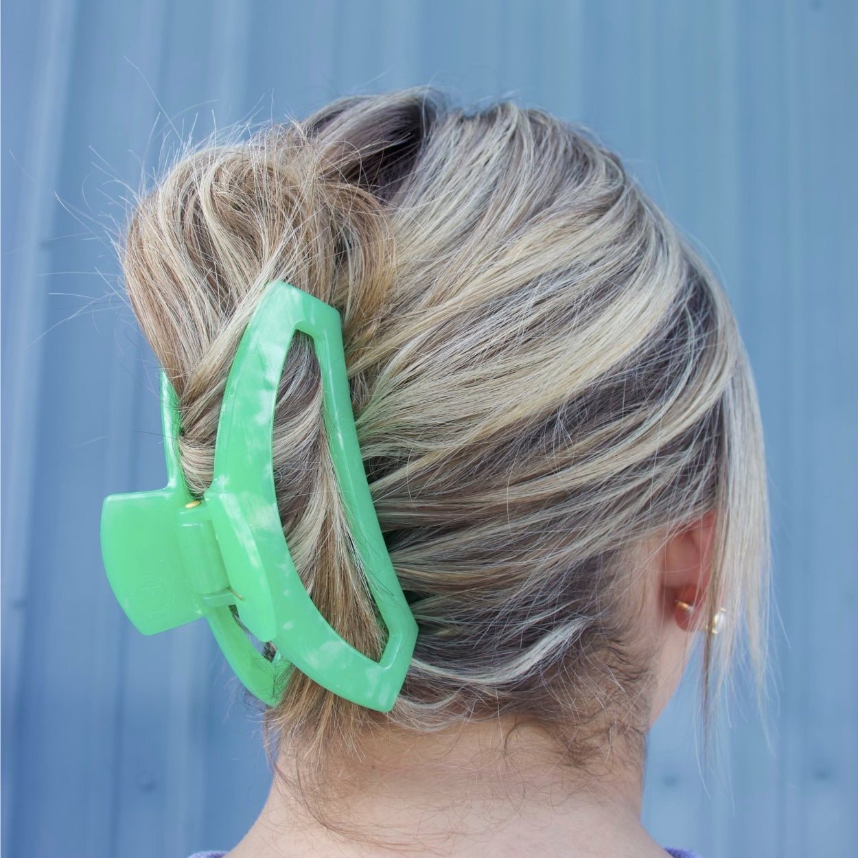 Large mint green hair clip clipped into a bun on dark blonde hair