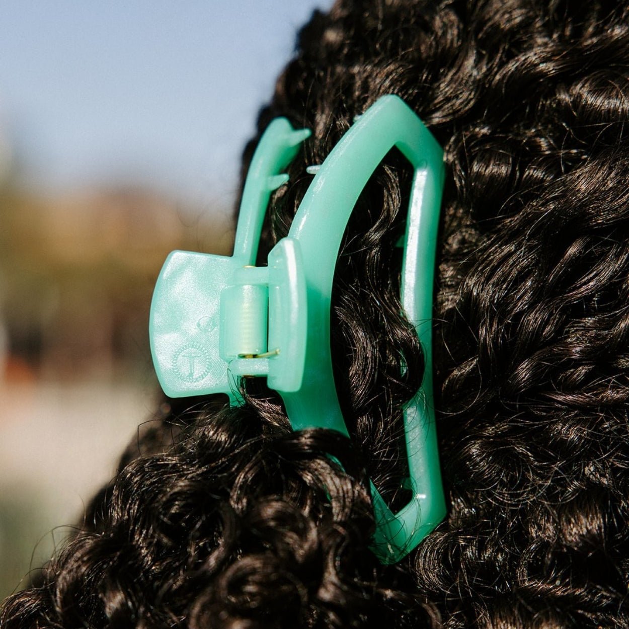 Mint green medium hair clip holding thick dark hair