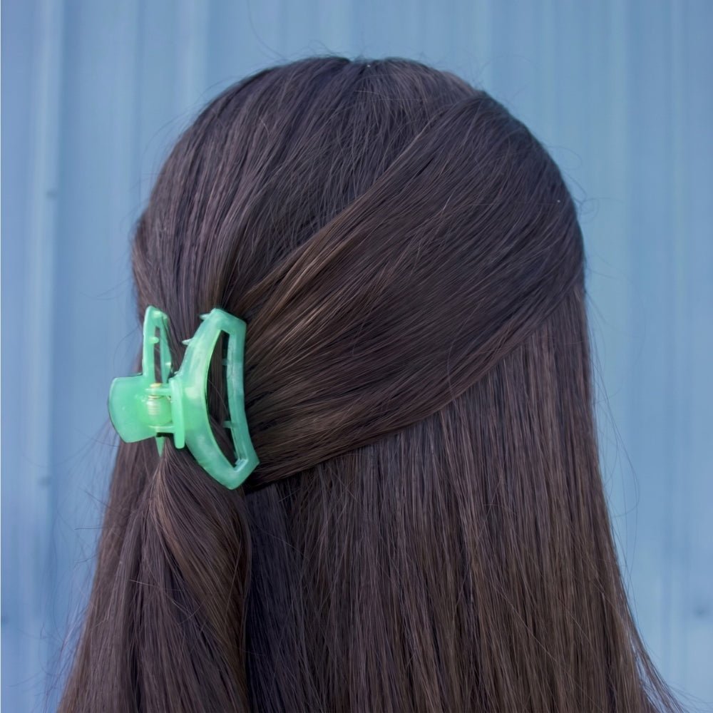 Small translucent green hair clip clipped to dark brown hair