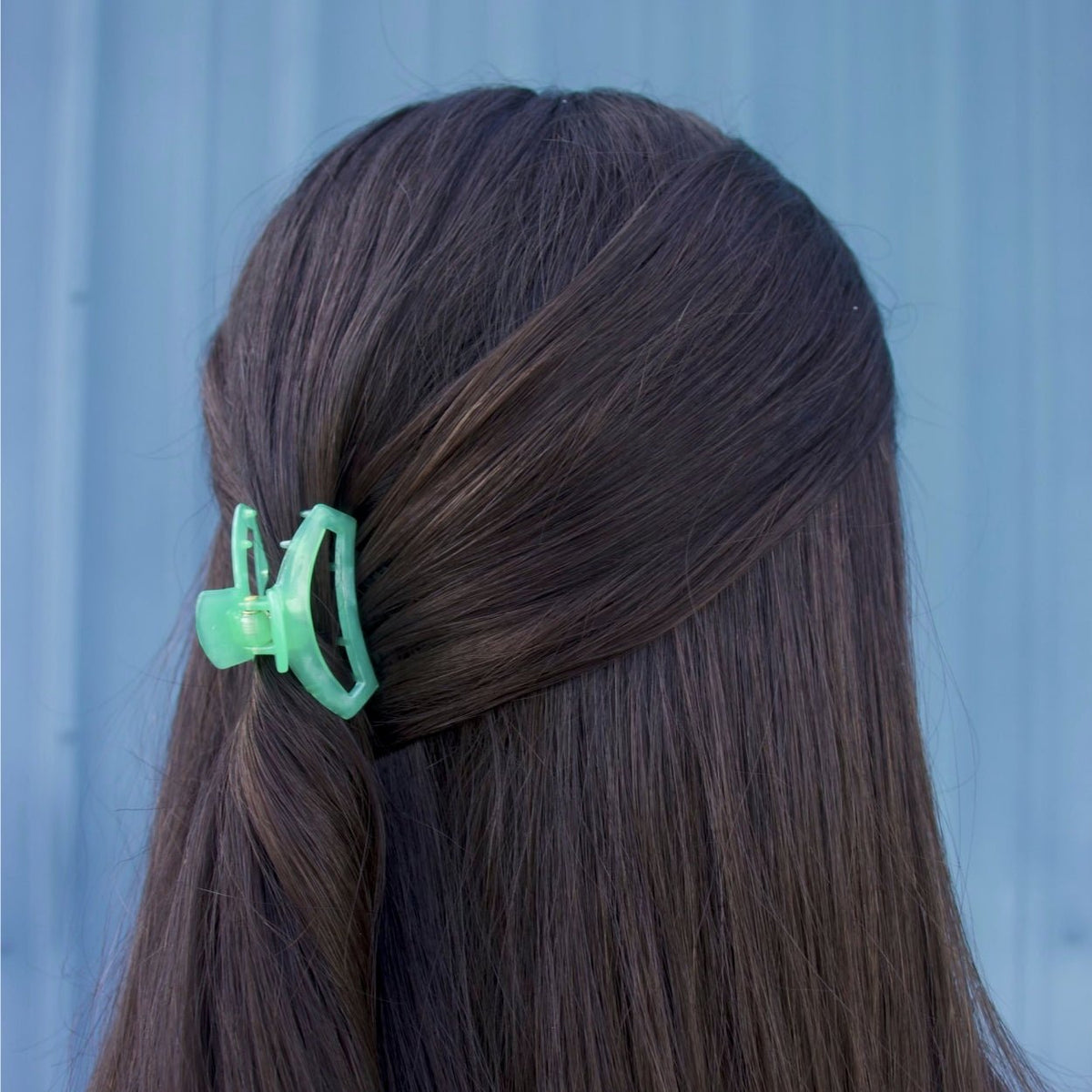 Mint-green open spring hair clip holding dark brown hair on the side.