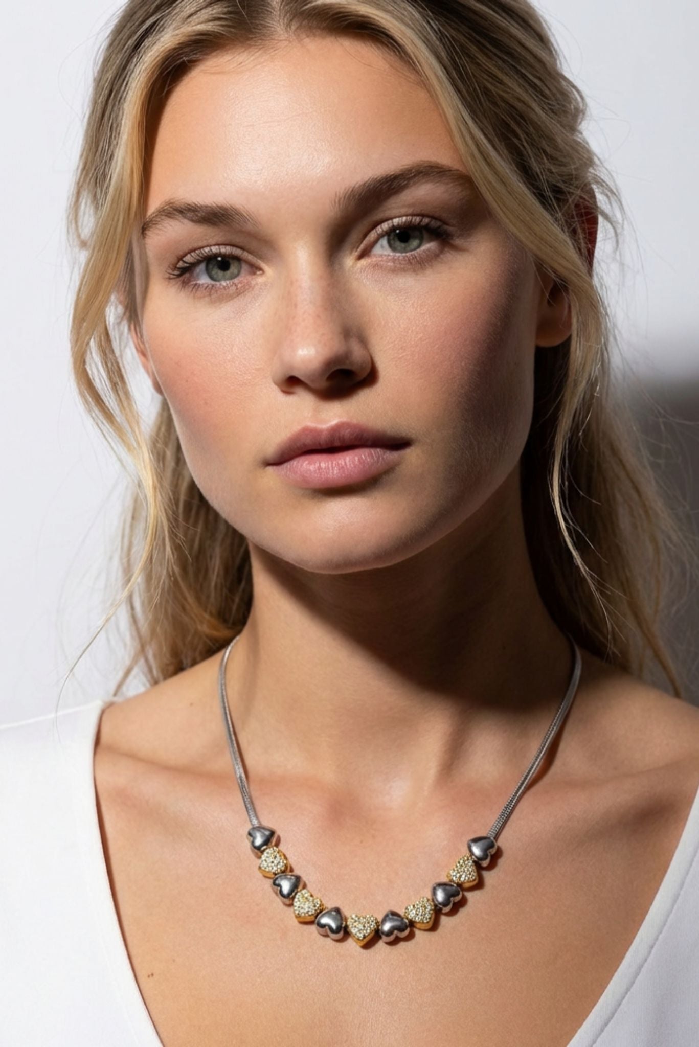 Silver-tone Y-necklace with small gold and white beads on model neckline
