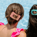 Large striped rectangle hair clip holding two hair sections, pink and green stripes.